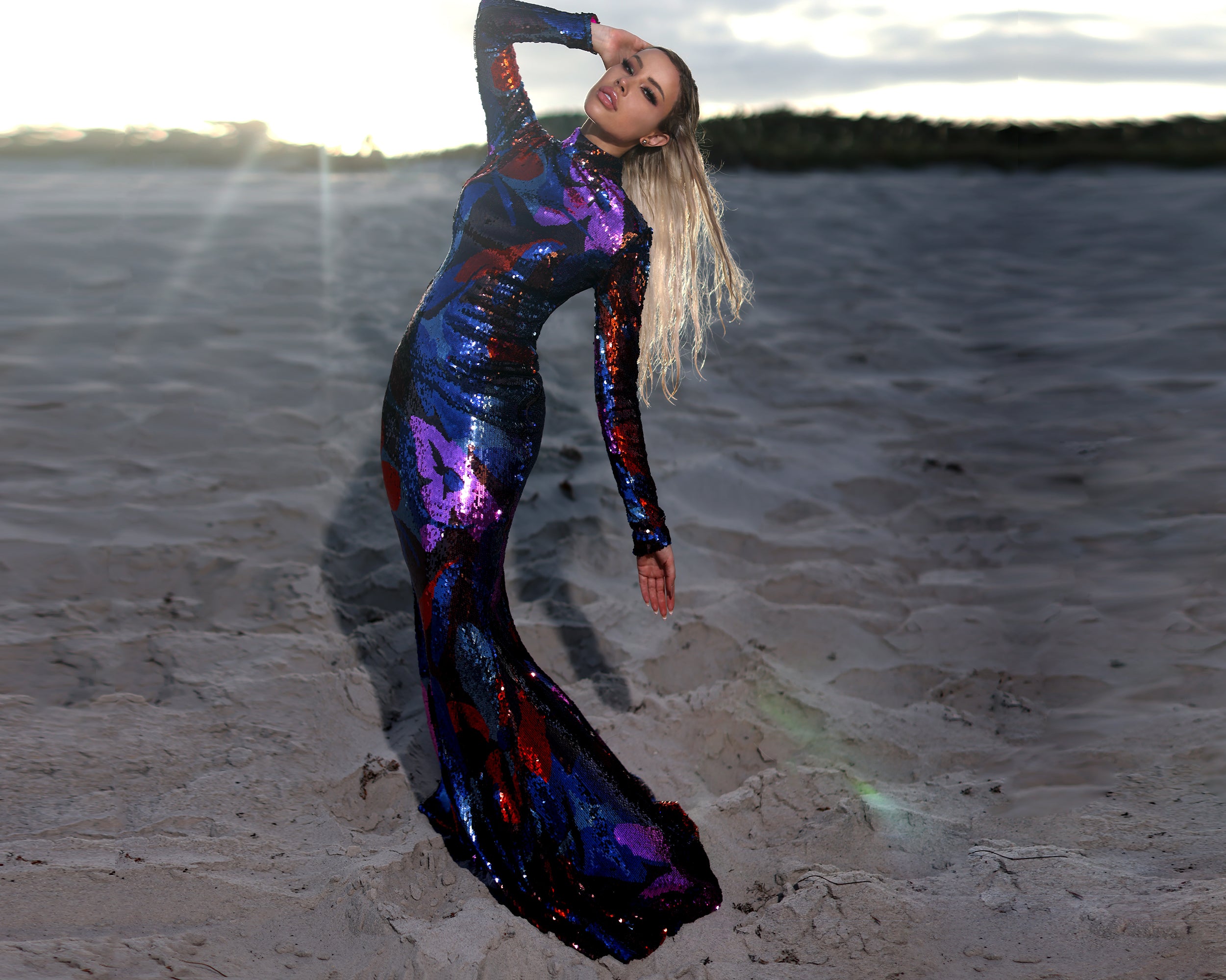 beautiful woman wearing a long mermaid sequin gown on the beach